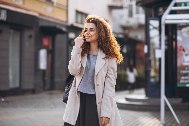 Linda mujer con cabello rizado caminando en una calle de café