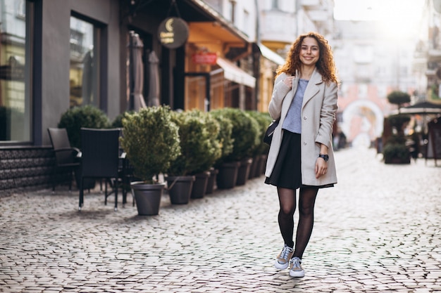 Linda mujer con cabello rizado caminando en una calle de café