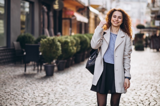 Linda mujer con cabello rizado caminando en una calle de café