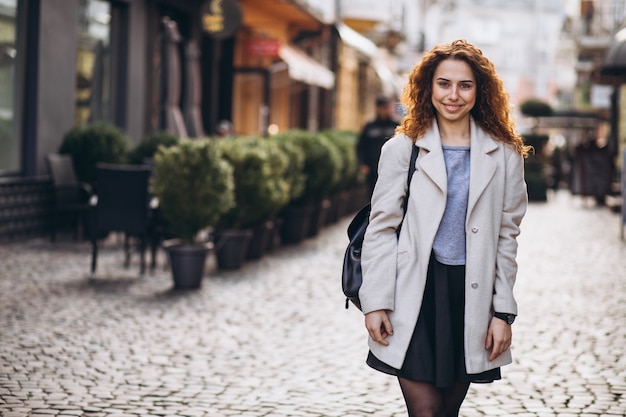 Linda mujer con cabello rizado caminando en una calle de café