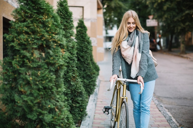 Linda mujer caminando con bicicleta