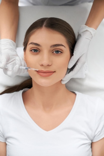 Foto gratuita linda mujer con camisa blanca en el procedimiento de inyección en el labio