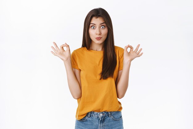 Linda mujer caucásica tonta y juguetona en camiseta amarilla haciendo pucheros juguetonamente haciendo una expresión tonta y divertida sonriendo feliz mostrando bien o signo de perfección dar aprobación recomendar algo