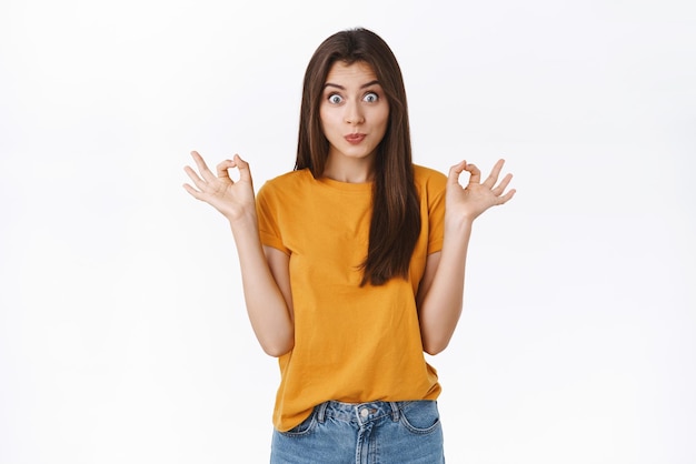 Linda mujer caucásica tonta y juguetona en camiseta amarilla haciendo pucheros juguetonamente haciendo una expresión tonta y divertida sonriendo feliz mostrando bien o signo de perfección dar aprobación recomendar algo