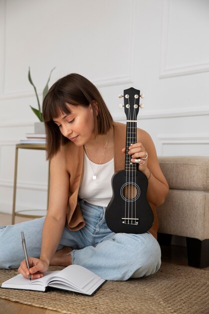 Linda mujer componiendo una nueva canción en ukelele