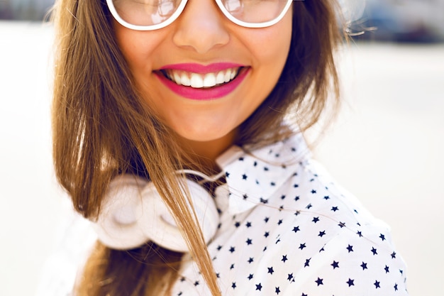 Linda mujer divirtiéndose en la calle, vestida con un vestido blanco divertido y auriculares blancos