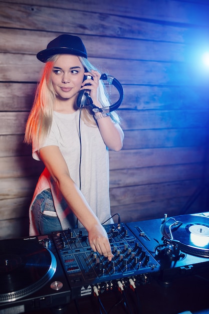 Linda mujer dj divirtiéndose tocando música en la fiesta del club