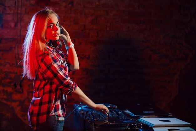 Linda mujer dj divirtiéndose tocando música en la fiesta del club