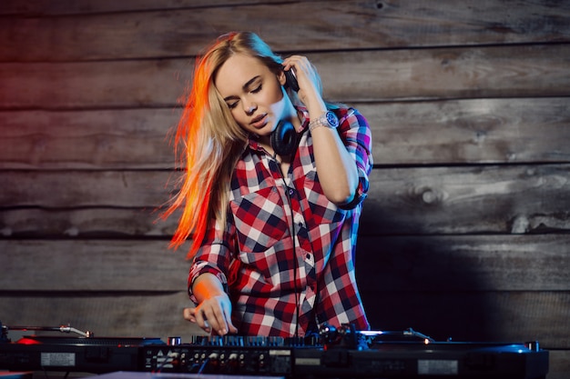 Linda mujer dj divirtiéndose tocando música en la fiesta del club