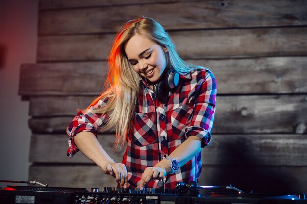 Linda mujer dj divirtiéndose tocando música en la fiesta del club