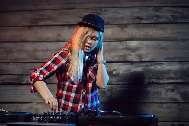 Linda mujer dj divirtiéndose tocando música en la fiesta del club