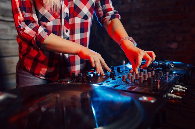 Linda mujer dj divirtiéndose tocando música en la fiesta del club