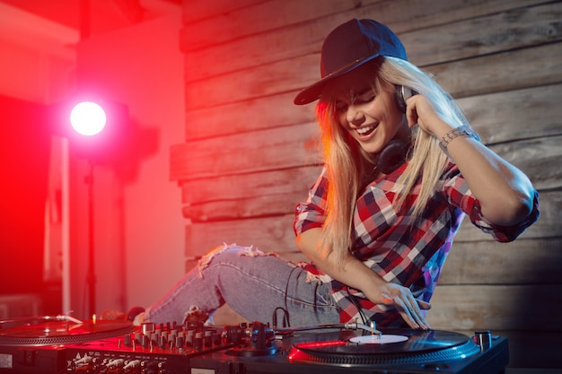 Linda mujer dj divirtiéndose tocando música en la fiesta del club