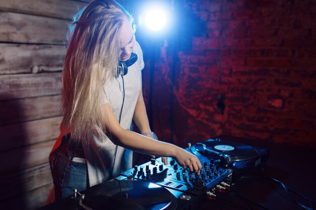 Linda mujer dj divirtiéndose tocando música en la fiesta del club