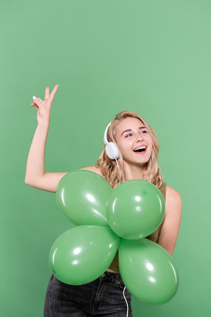 Linda mujer escuchando música y sosteniendo globos