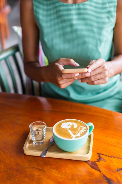 Linda mujer feliz tranquila elegante en vestido verde de verano se sienta con café en la cafetería disfrutando de la mañana