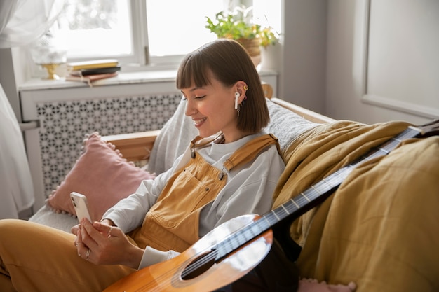 Foto gratuita linda mujer guitarrista comprobando su teléfono