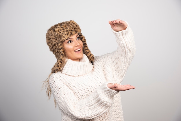 Una linda mujer con un hermoso sombrero sobre un fondo gris.