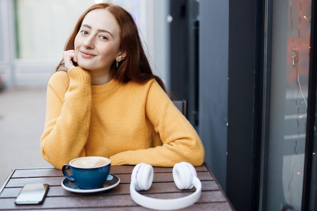 linda mujer joven con café en la cafetería al aire libre