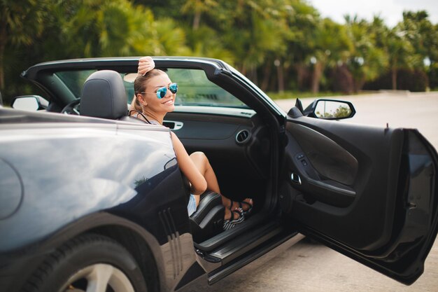 Linda mujer joven en coche descapotable