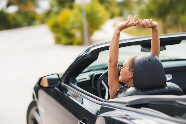 Foto gratuita linda mujer joven en coche descapotable