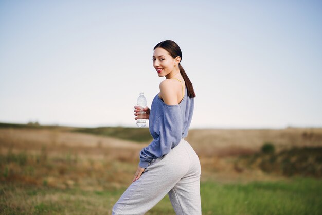 Linda mujer joven entrenando con una botella de agua