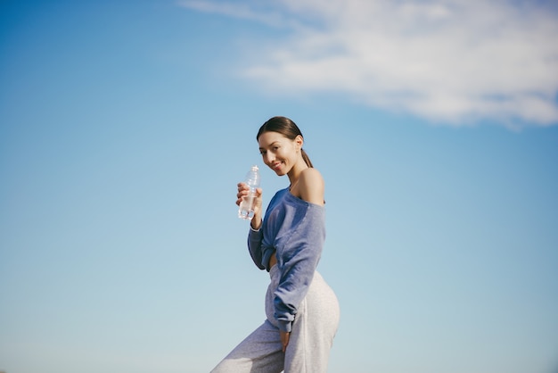 Linda mujer joven entrenando con una botella de agua