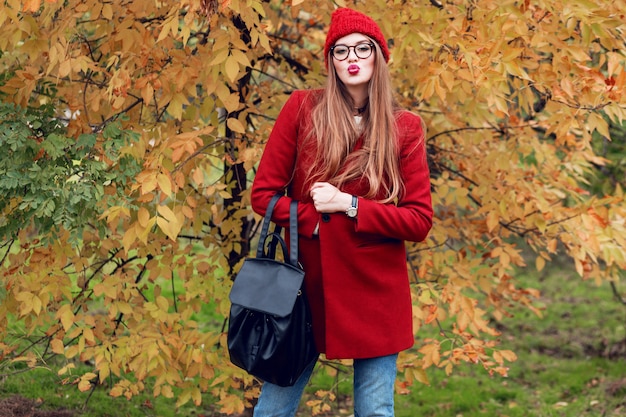 Linda mujer joven enviar beso. Señora atractiva con ropa roja de otoño