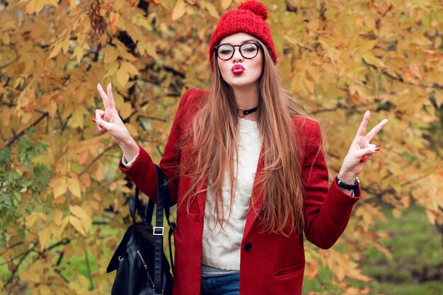 Linda mujer joven enviar beso. Señora atractiva con ropa roja de otoño