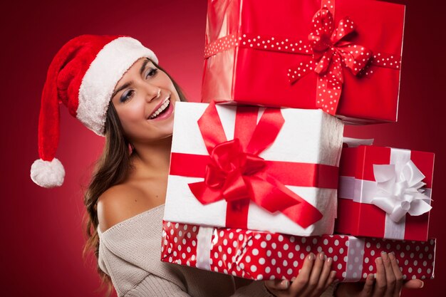 Linda mujer joven con gorro de Papá Noel con regalos de Navidad
