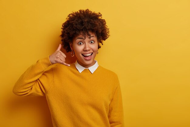 Linda mujer joven hace gesto de teléfono, muestra la señal de devolución de llamada