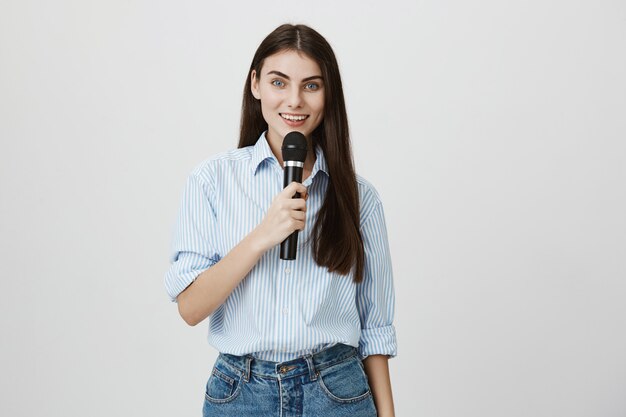 Linda mujer joven haciendo discurso en micrófono