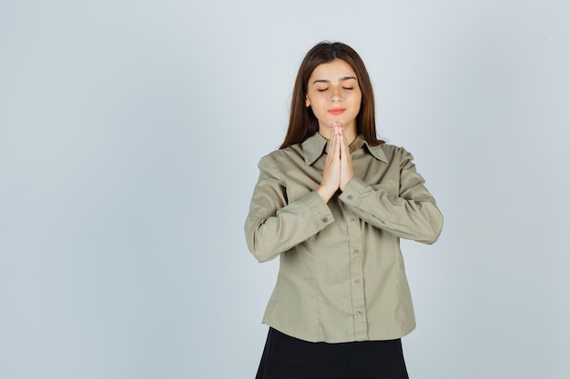 Foto gratuita linda mujer joven mostrando gesto de namaste en camisa, falda y mirando esperanzado, vista frontal.