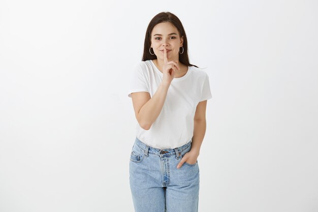 Linda mujer joven posando contra la pared blanca