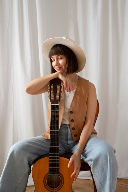 Linda mujer joven posando con una guitarra en el interior