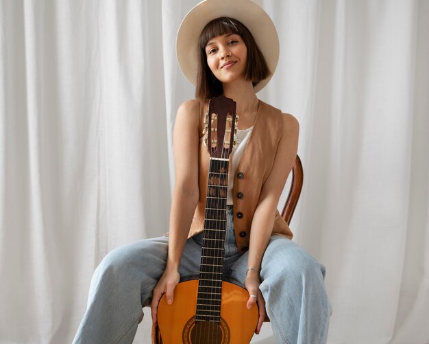 Linda mujer joven posando con una guitarra en el interior