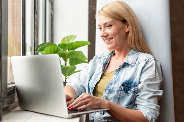 Foto gratuita linda mujer joven que trabaja en una computadora portátil