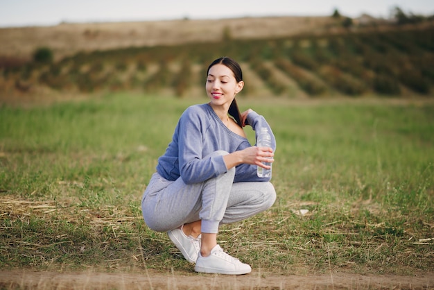 Linda mujer joven en ropa deportiva con botella de agua