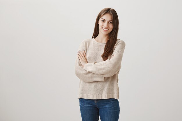 Linda mujer joven sonriendo a la cámara en gris