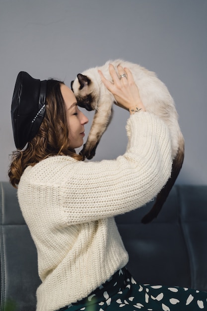 Linda mujer jugando con gato siamés