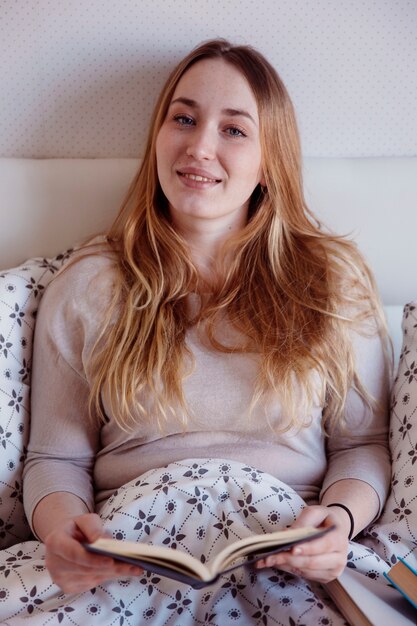 Linda mujer con libro en la cama