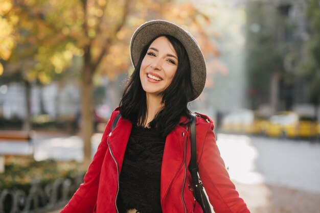 Linda mujer morena de pie en el parque con sonrisa feliz