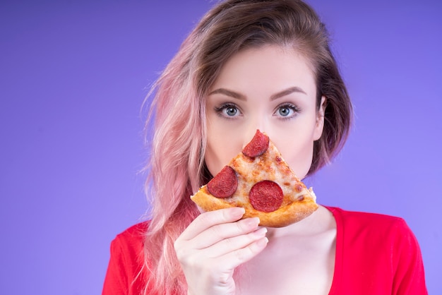 Linda mujer mostrando una rebanada de pizza de pepperoni