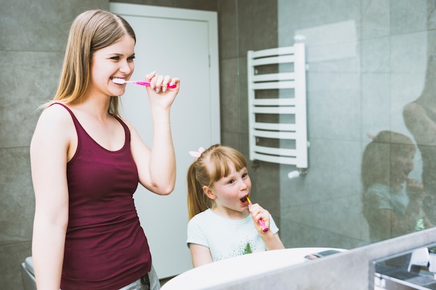 Linda mujer y niña cepillarse los dientes