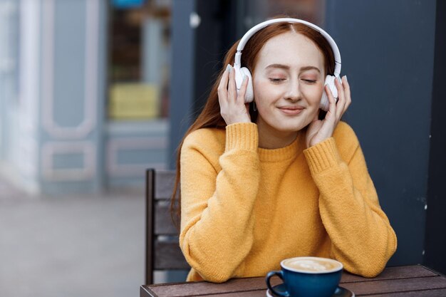 linda mujer pelirroja con auriculares al aire libre con ropa informal