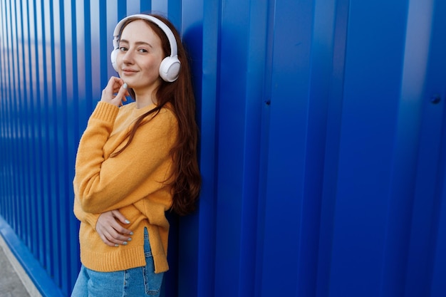 linda mujer pelirroja escucha música en los auriculares