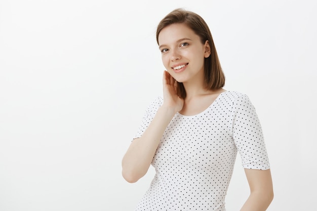 Linda mujer romántica mete el mechón de pelo detrás de la oreja y sonriendo tontamente