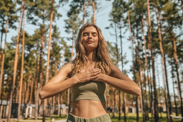 Linda mujer rubia practicando yoga afuera y luciendo relajada