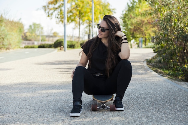 Foto gratuita linda mujer sentada en longboard