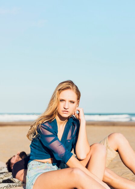 Linda mujer sentada en la playa cerca del hombre